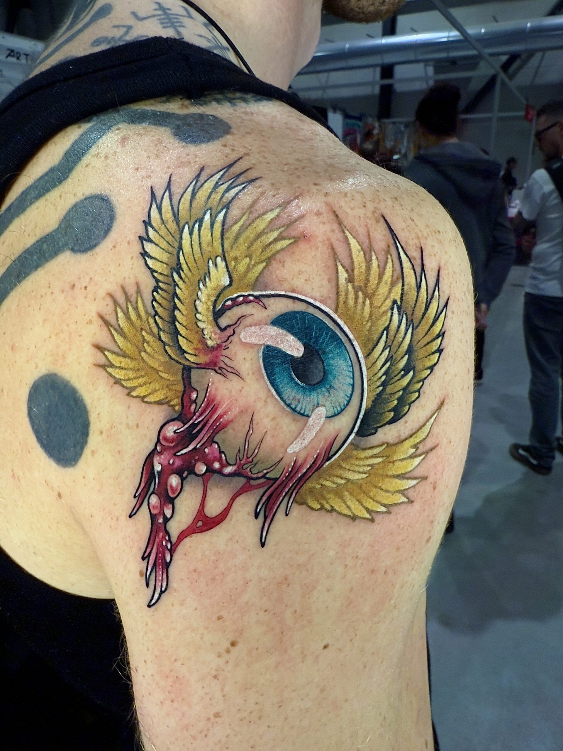 Kleurrijke neo traditional oogbal tattoo met vleugels en opvallende details