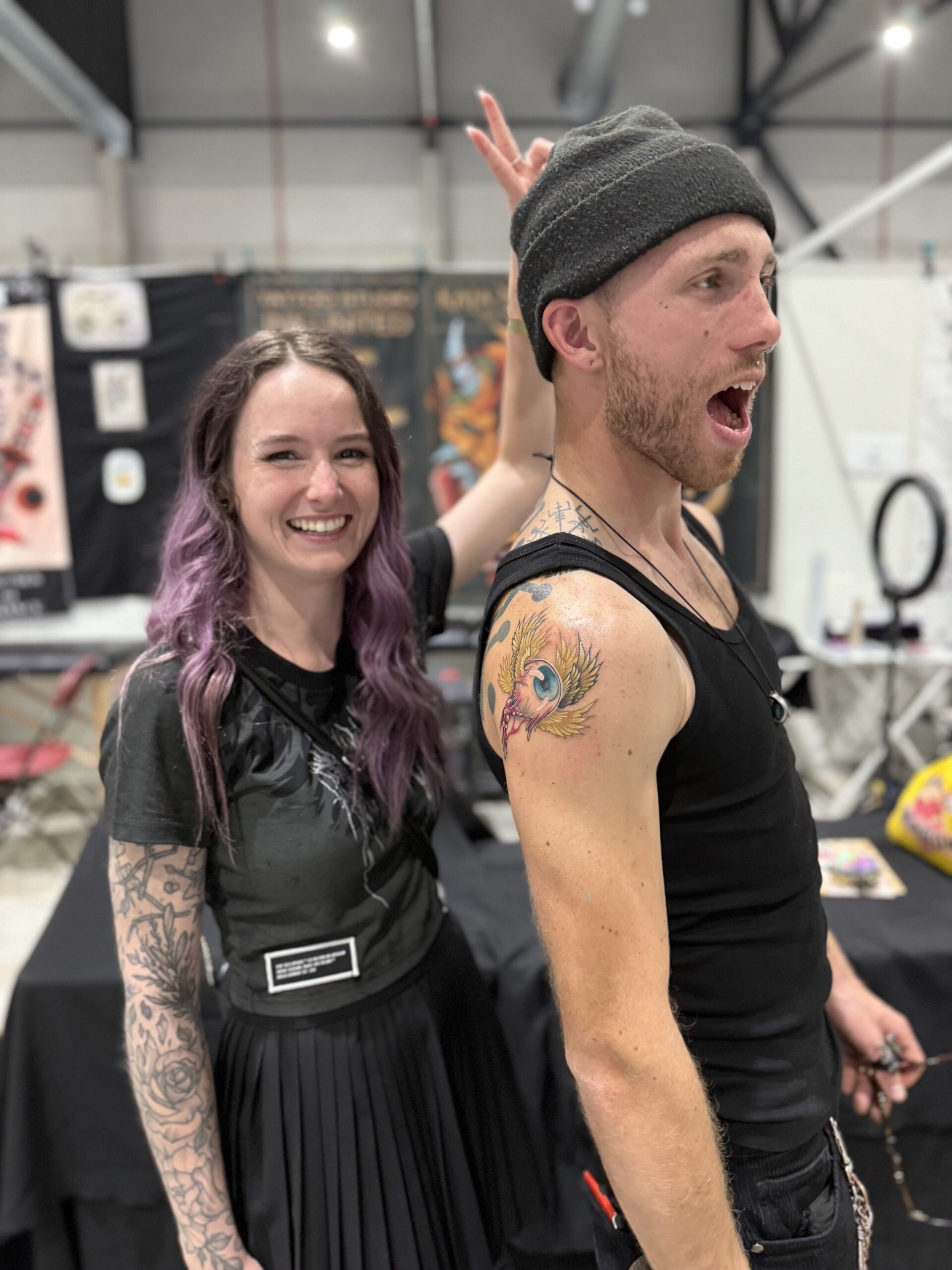 Tattoo artiest Kaja Nijssen poseert samen met een tevreden klant en een nieuw gezette tattoo tijdens een tattoo conventie